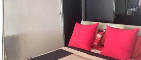 Une chambre d’hôtel avec un lit, un miroir et une fenêtre.