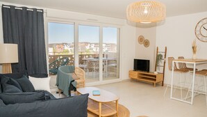 Ein modernes Wohnzimmer mit einer Couch, einem TV-Schrank und einem Essbereich mit Stühlen und einem Tisch.