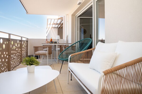 A balcony with a white sofa, a dining table, and chairs.