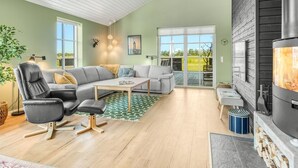 Una sala de estar moderna con chimenea, un conjunto de sofás, una mesa de comedor y vistas al exterior a través de puertas de vidrio.