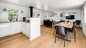 A modern kitchen with white cabinets, a wooden dining table, and a black sofa.