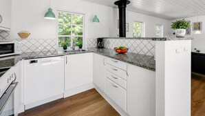 A modern kitchen with white cabinets, granite countertops, and a black range hood.