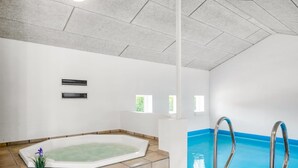 A spa room with a hot tub, a small pool, and a staircase leading to the pool.