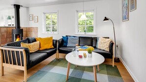 A modern living room with a black leather sofa, a wooden bench, a white coffee table, and a fireplace.