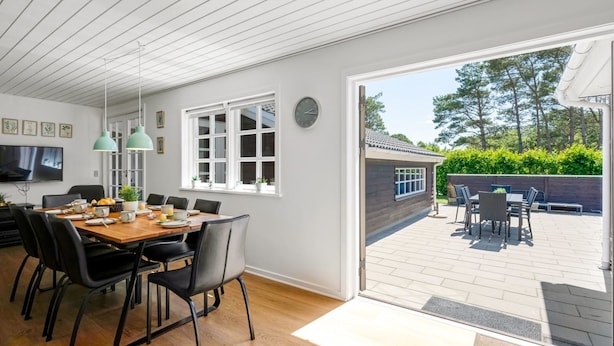 A modern kitchen with a dining area, large windows, and a view of the outdoor patio.