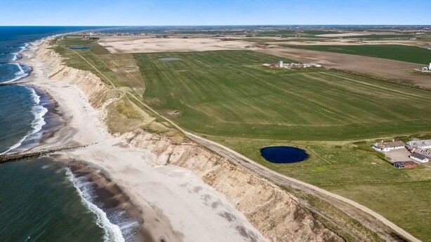 An aerial view of a coastal area with a beach, green fields, and a small body of water. - "Vili" - 100m from the sea by Interhome (Lemvig)
