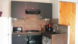 A compact kitchen with a built-in oven, a gas stove, and a coffee maker.