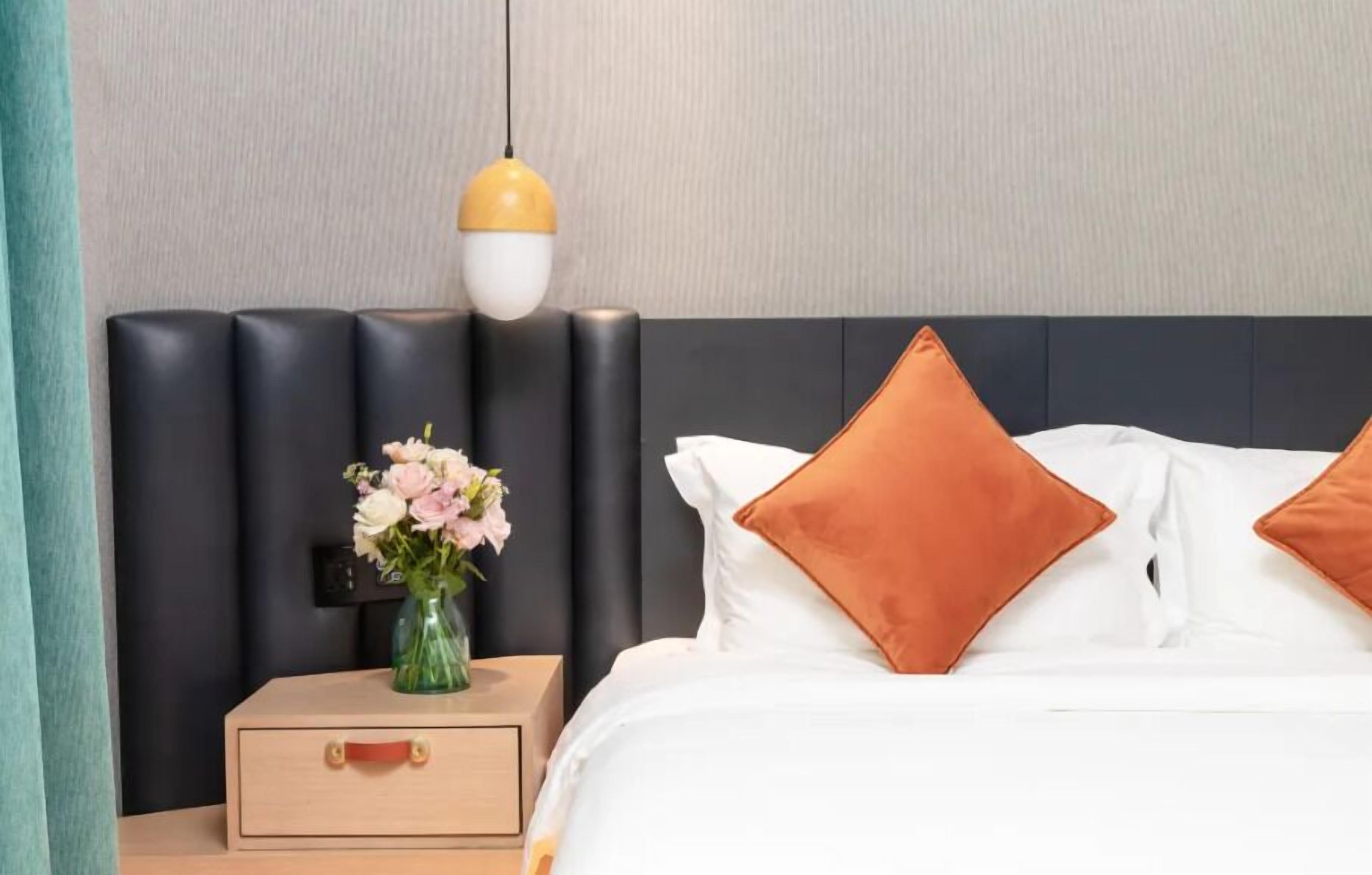 Un dormitorio ordenado con cama, mesita de noche y un florero.