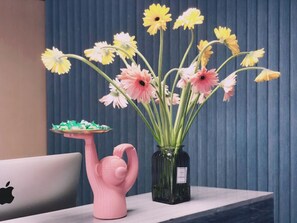 A desk with a laptop, a pink flamingo-shaped vase, and a green vase with flowers. - Puyue Hotel - Shenzhen East Railway Station Buji Metro Station (Shenzhen)