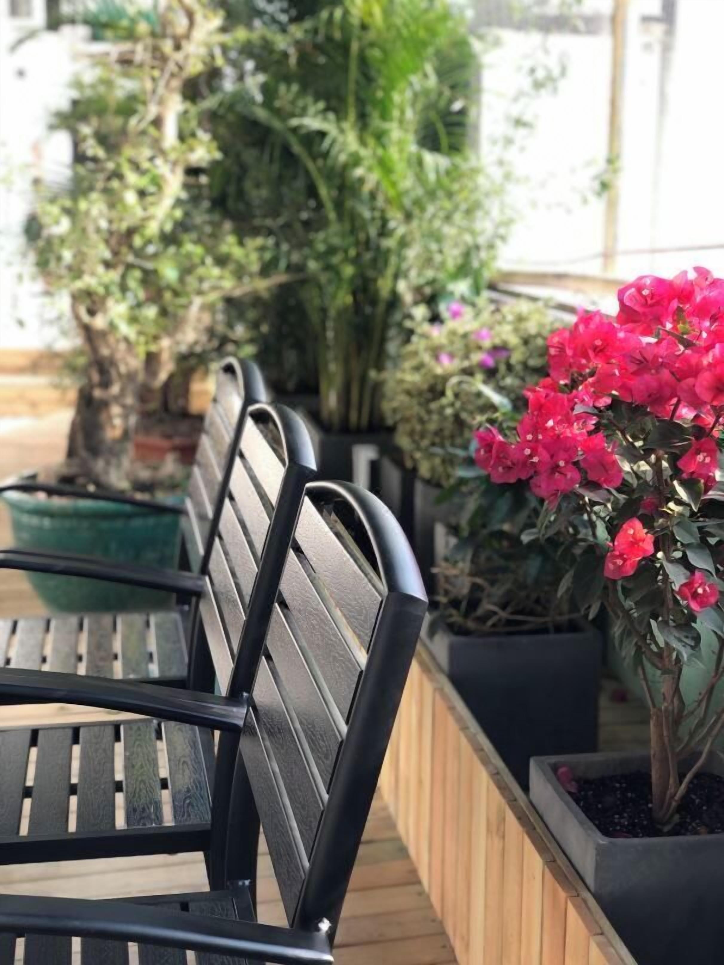 Une rangée de bancs en métal noir, avec un plancher en bois en arrière-plan.