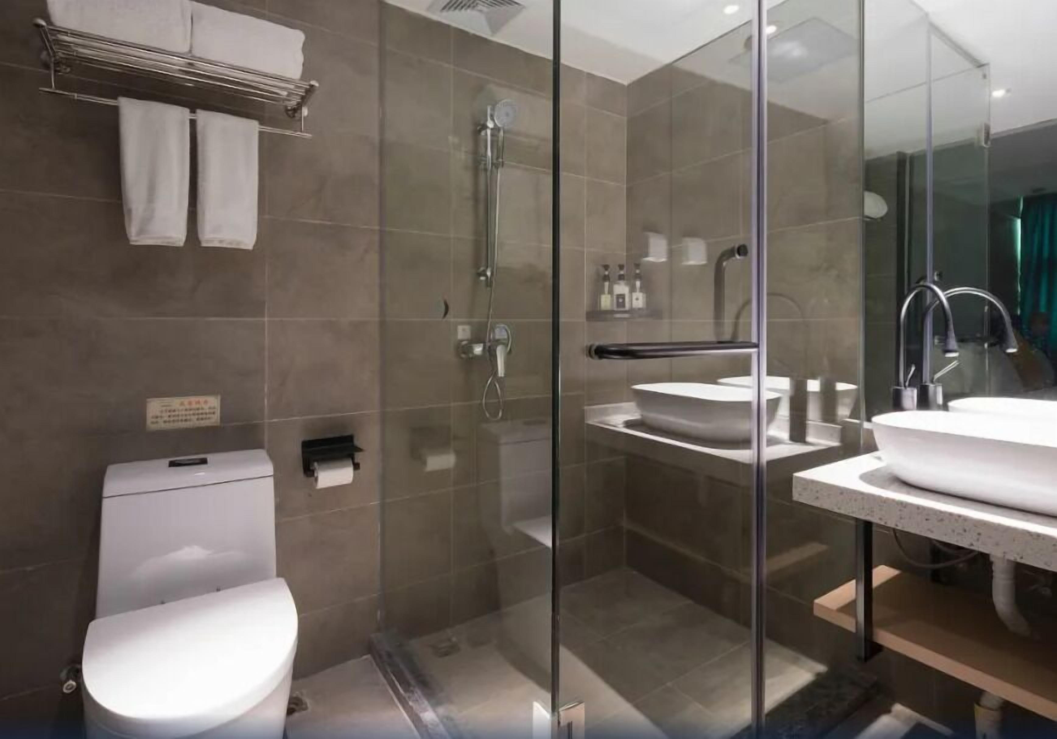 Un baño moderno con ducha de vidrio, inodoro y lavamanos con espejo.