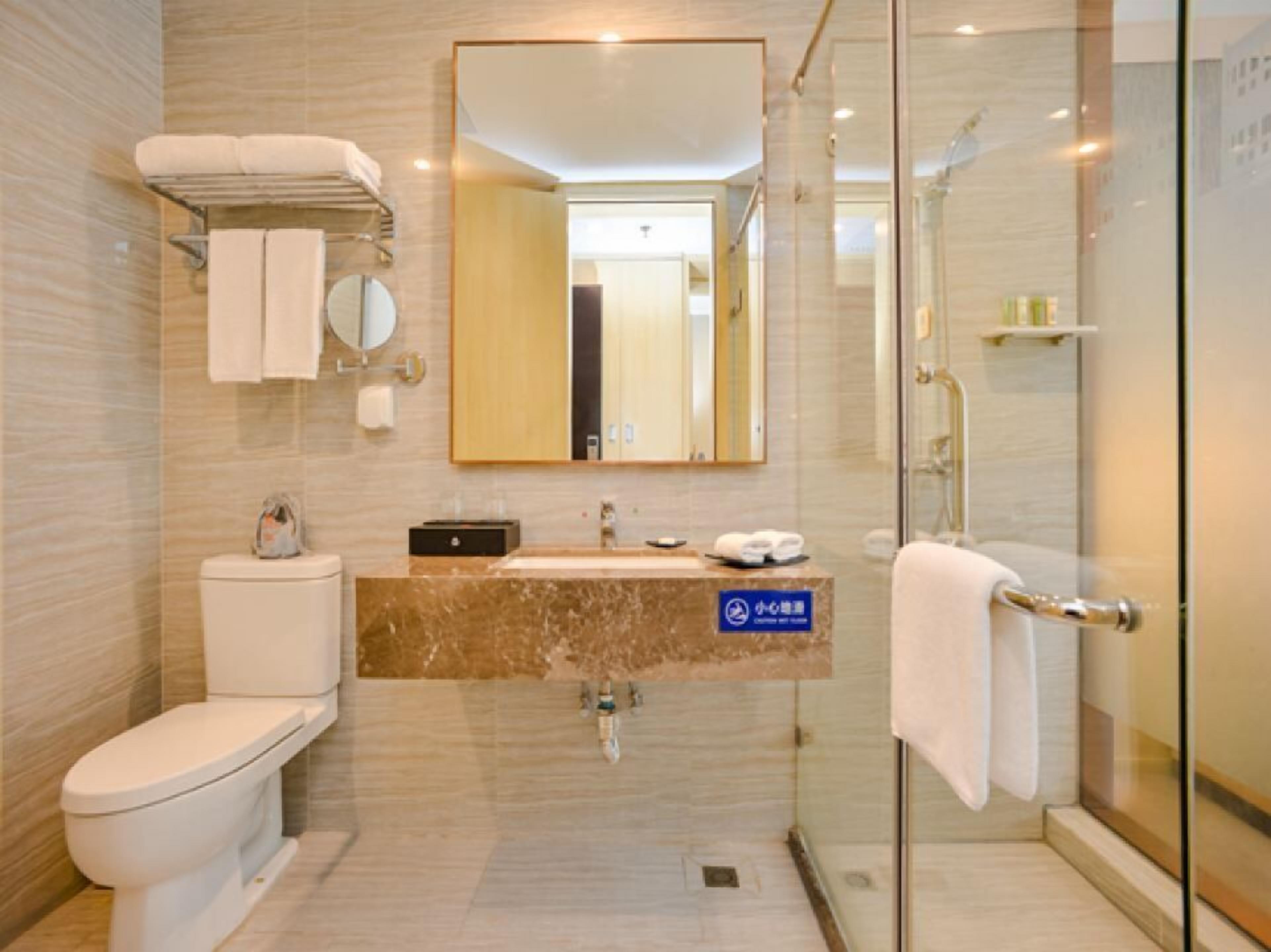 A modern bathroom with a toilet, sink, and glass shower enclosure.