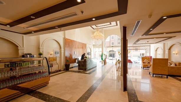 A spacious lobby with a reception desk, a water fountain, and seating areas. - Holiday Plus Al Nuzha (Jeddah)