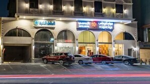 A multi-story hotel with a modern facade, featuring large windows and a prominent entrance with signage. - Holiday Plus Al Nuzha (Jeddah)