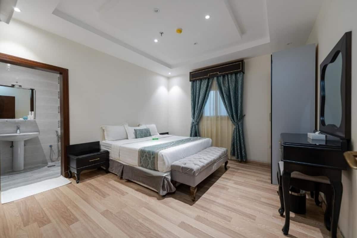 A bedroom with a bed, bedside tables, a desk, and a mirror.