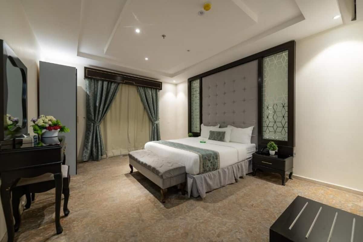 A modern bedroom with a bed, bedside tables, a dresser, and a mirror.