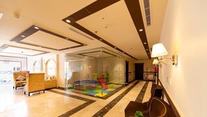 A lobby with a play area, seating, and a glass partition. - Holiday Plus Al Nuzha (Jeddah)