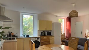 A compact kitchen with a dining area, a washing machine, and a large window providing natural light. - Apartment Chateau Rouge  (La Londe-les-Maures)