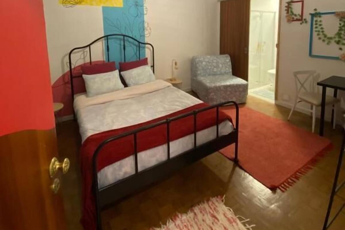 Une chambre à coucher comprenant un lit, une chaise, une petite table et un luminaire suspendu.