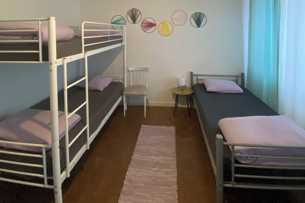 Une chambre de dortoir avec des lits superposés, une petite table, une chaise et une décoration murale.