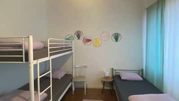Un dormitorio con literas, una mesa pequeña, una silla y un adorno en la pared.