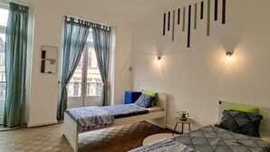 A bedroom with two beds, a small table, and a window with curtains. - Barão 35 Guest House (Braga)