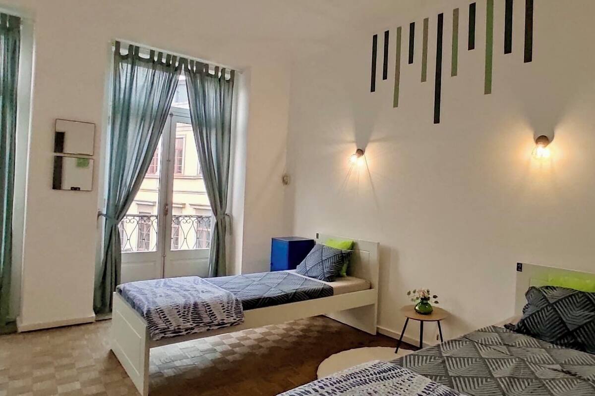 Une chambre avec deux lits, une petite table et une fenêtre avec des rideaux.
