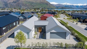 A residential area with modern houses, a driveway, and a mountain backdrop. - Lake View Heights - Luxury large modern House (244 sq mtr)  (Wanaka)