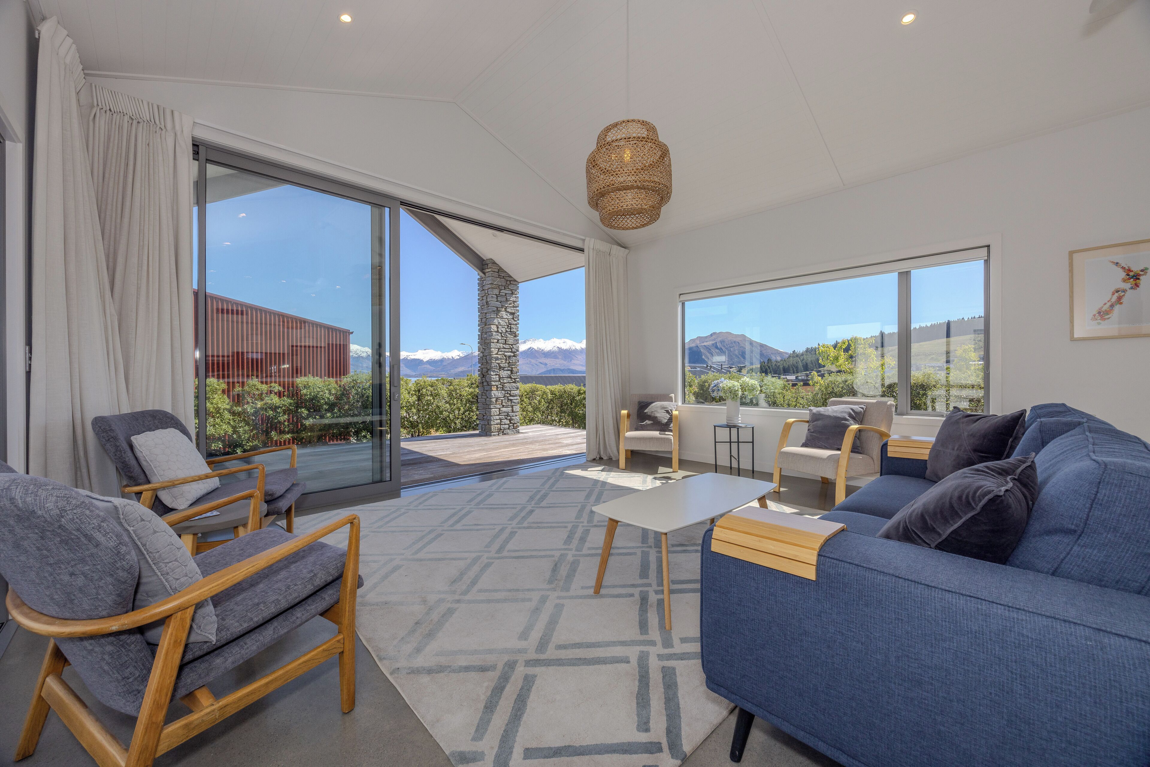 Un salon moderne avec un canapé, des fauteuils, une table et une vue sur les montagnes grâce à de grandes fenêtres.