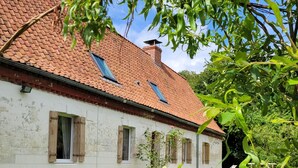 A rustic building with a red-tiled roof, white walls, and wooden shutters. - Maison 1810, the charm of old stones. (Fosseux)
