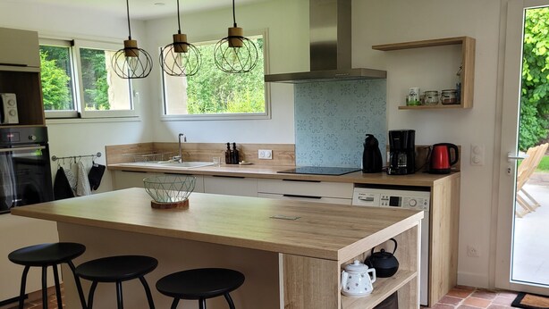 A modern kitchen with a large island, bar stools, a built-in oven, and a coffee maker. - Maison 1810, the charm of old stones. (Fosseux)