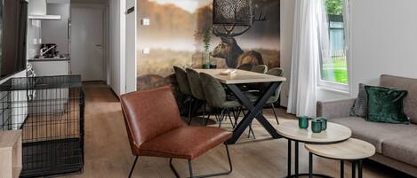 A modern living room with a dining area, a sofa, a coffee table, and a kitchen in the background.