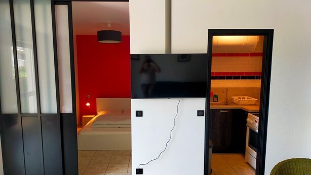 Eine moderne Küche mit roter Akzentwand, schwarzem Arbeitsplatz und sichtbarem Herd.