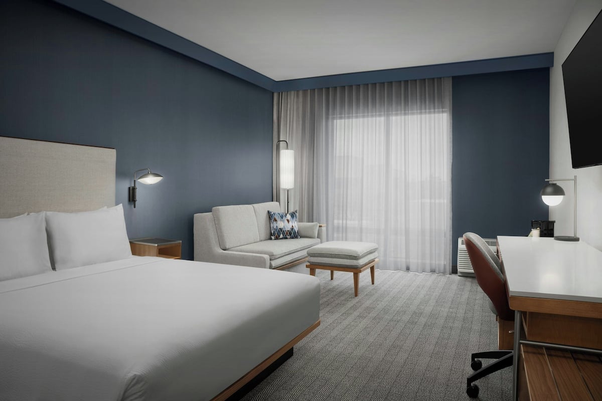 A hotel room with a large bed, a sofa, a desk, and a chair.