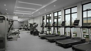 A modern gym with treadmills, elliptical machines, and weight equipment.