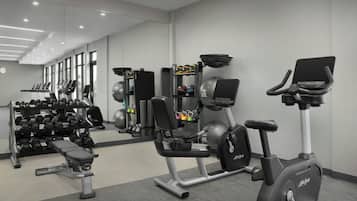 A gym with various exercise equipment, including treadmills, weight machines, and a bench.