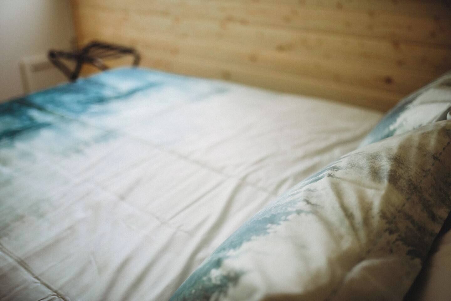 Una cama con una colcha blanca y azul estampada y un almohadón con un diseño similar.