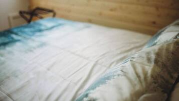 Una cama con una colcha blanca y azul estampada y un almohadón con un diseño similar.