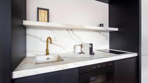 Eine moderne Küche mit Marmorarbeitsplatte, Armatur aus Gold und einem eingebauten Ofen.