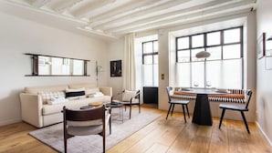 Ein modernes Wohnzimmer mit einer Couch, Sesseln, einem Esstisch und großen Fenstern.