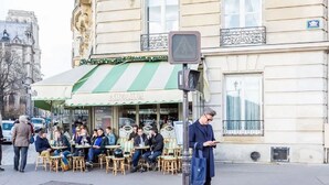 Ein Café mit Außenbereich, einer grün-weiß gestreiften Markise und einer Fußgängerampel.