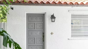 A white building with a grey door featuring a decorative panel design. - Heart of Calle 8 | Spacious 2/2 for Families (Miami)
