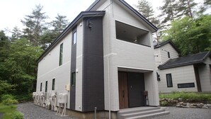 Una moderna casa a due piani con un'ampia porta garage e una zona relax coperta all'aperto.
