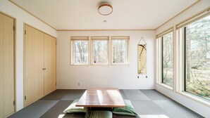 Una stanza con pavimento in tatami, un tavolino e ampie finestre.