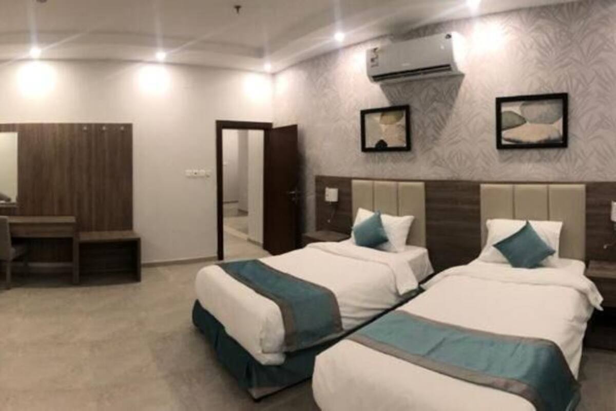 A hotel room with two beds, a desk, and a chair.