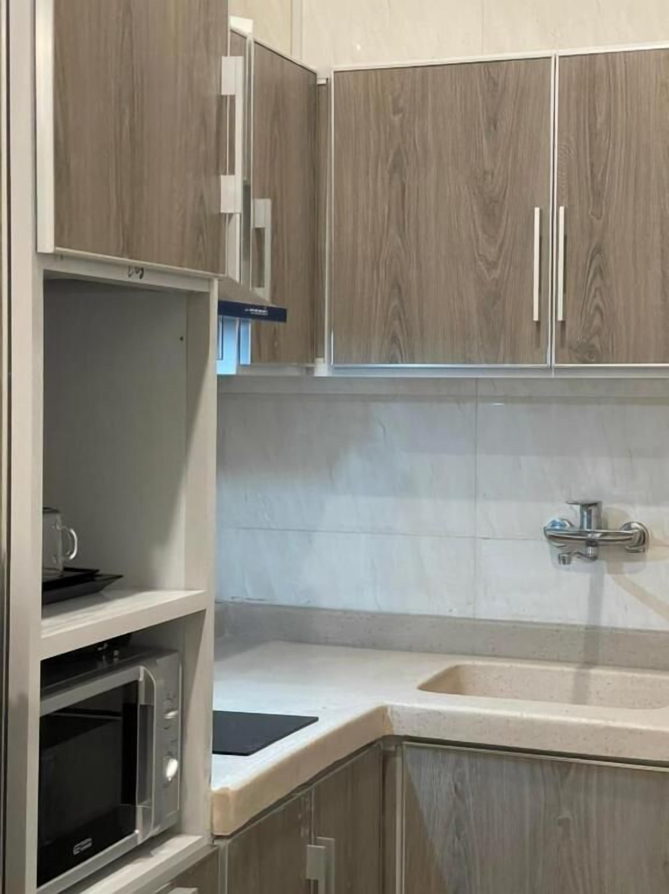 A modern kitchen with wooden cabinets, a built-in microwave, and a sink.