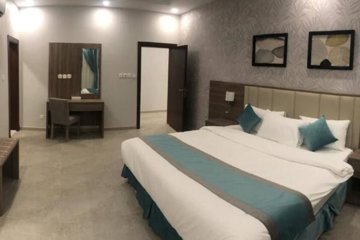A hotel room with a large bed, a desk, and a wardrobe.