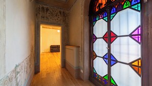 A hallway with wooden flooring, a door leading to a room, and a stained glass window with geometric patterns. - Palazzo Salviati Quaratesi (Florence)