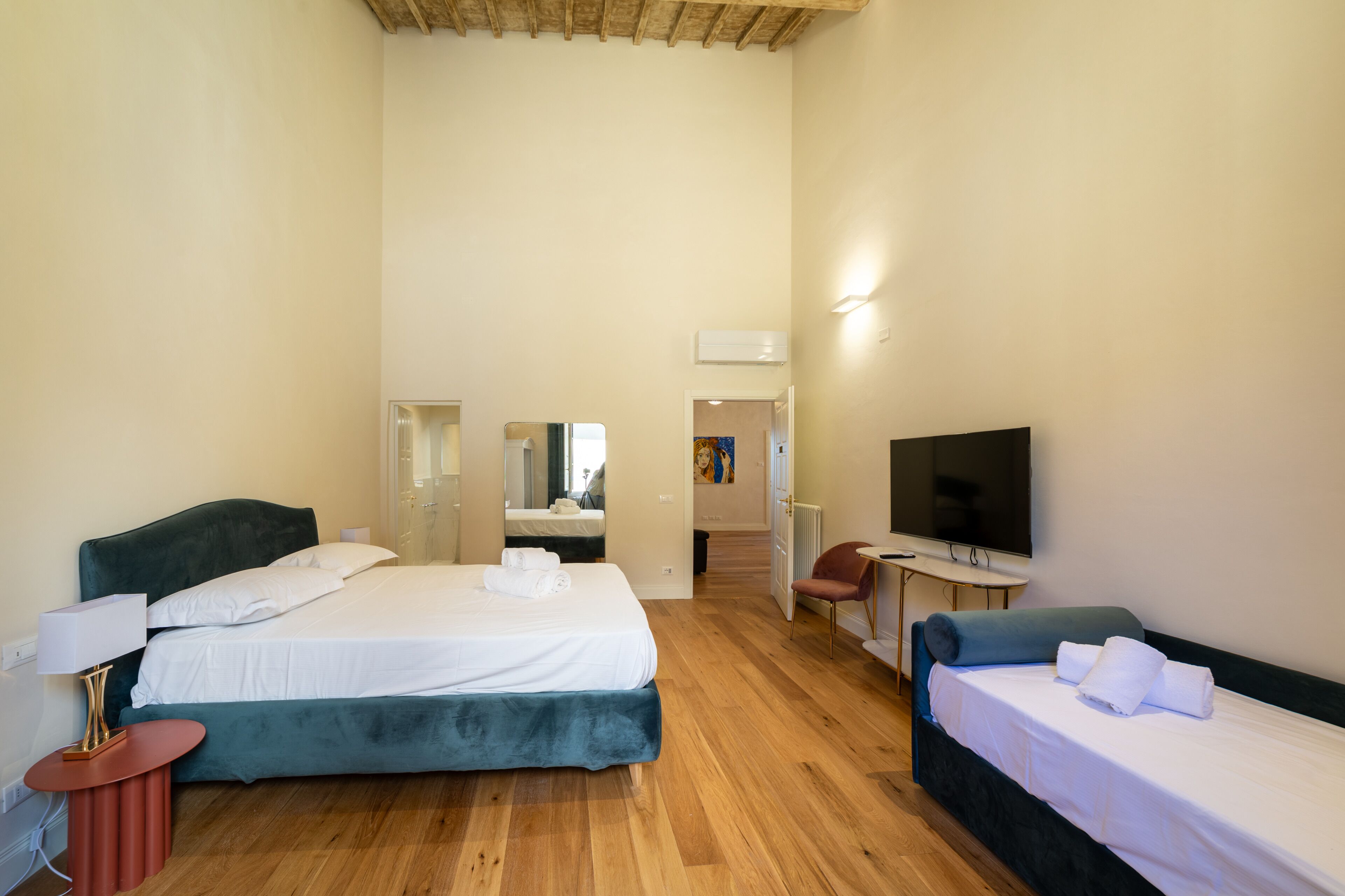 A hotel room with two beds, a desk, a chair, a TV, and a mirror.