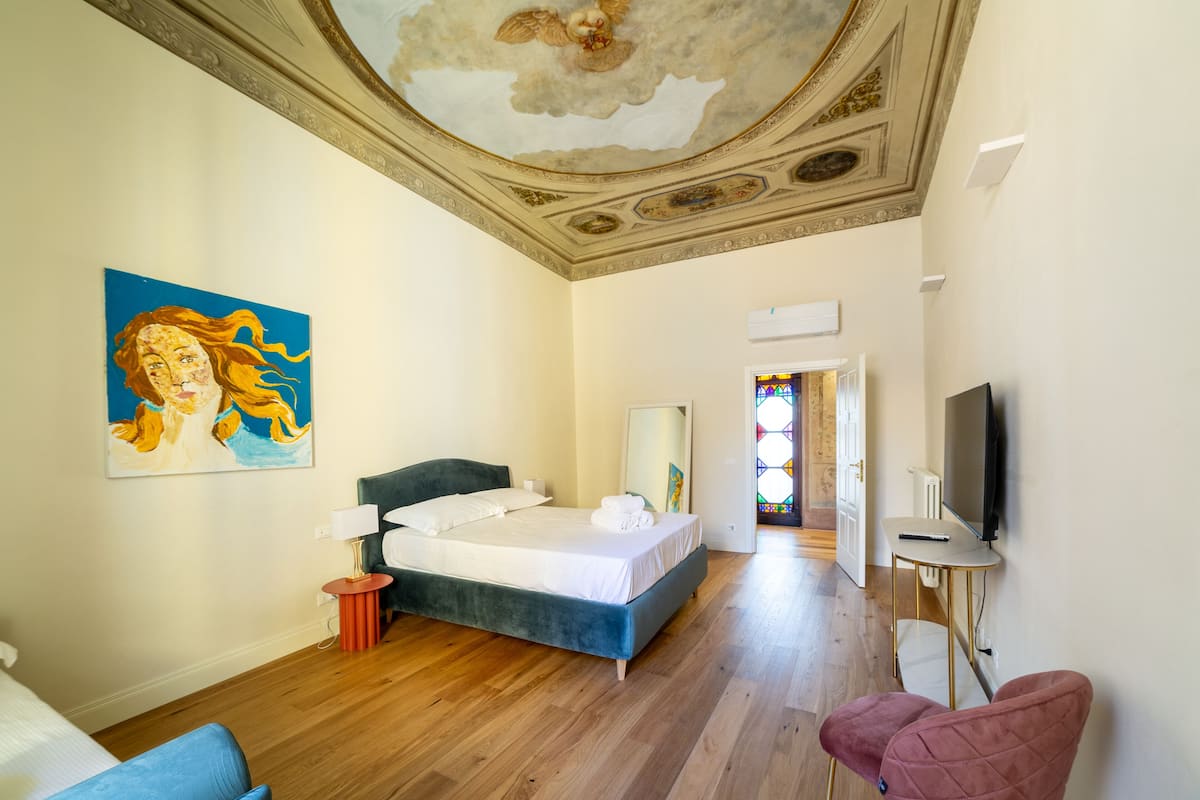 Une chambre d’hôtel avec un lit, une télévision, un tableau et une vue sur une église.